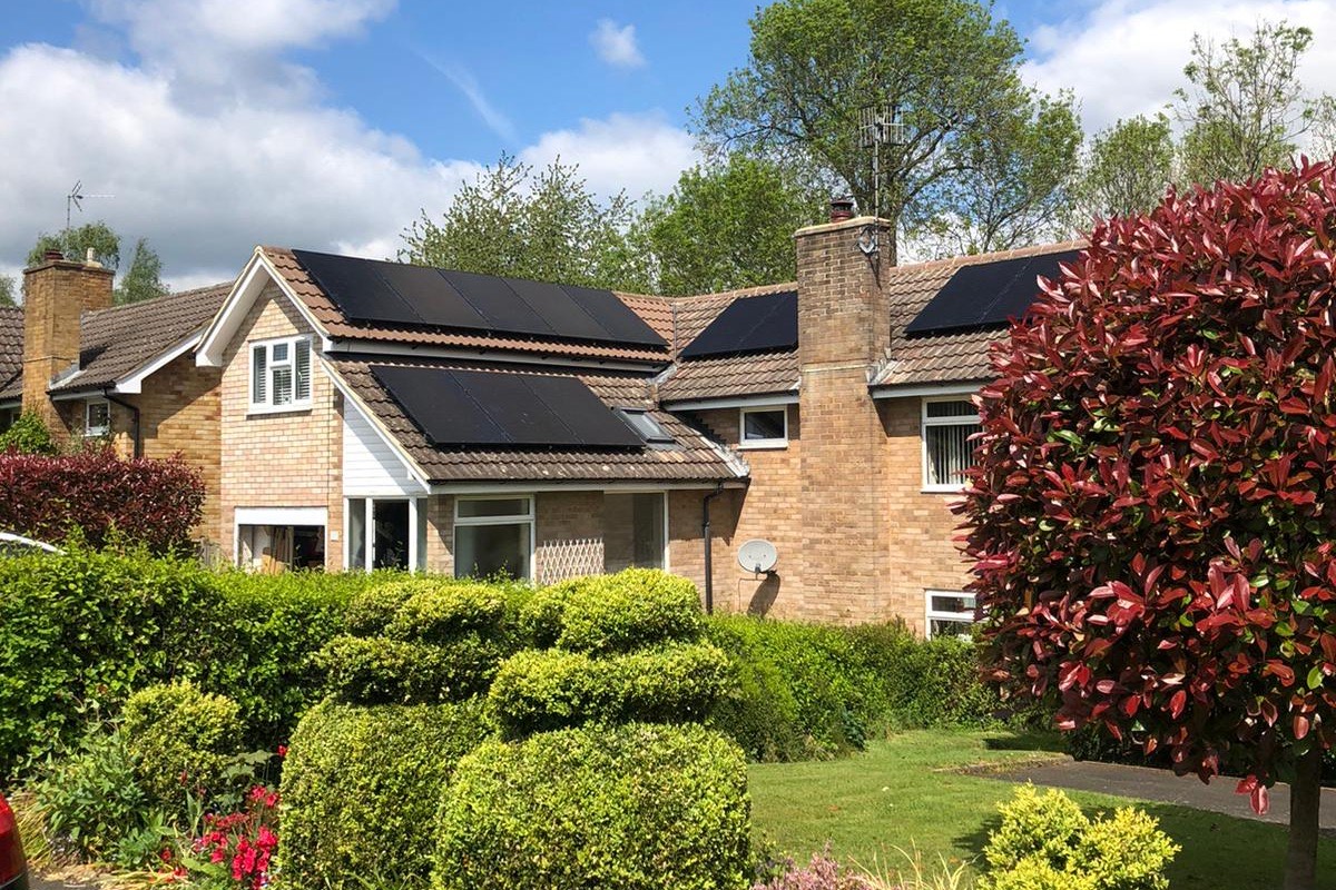A finished L&R solar PV installation: black panels on three tiled roof slopes of a brick house, on a sunny day