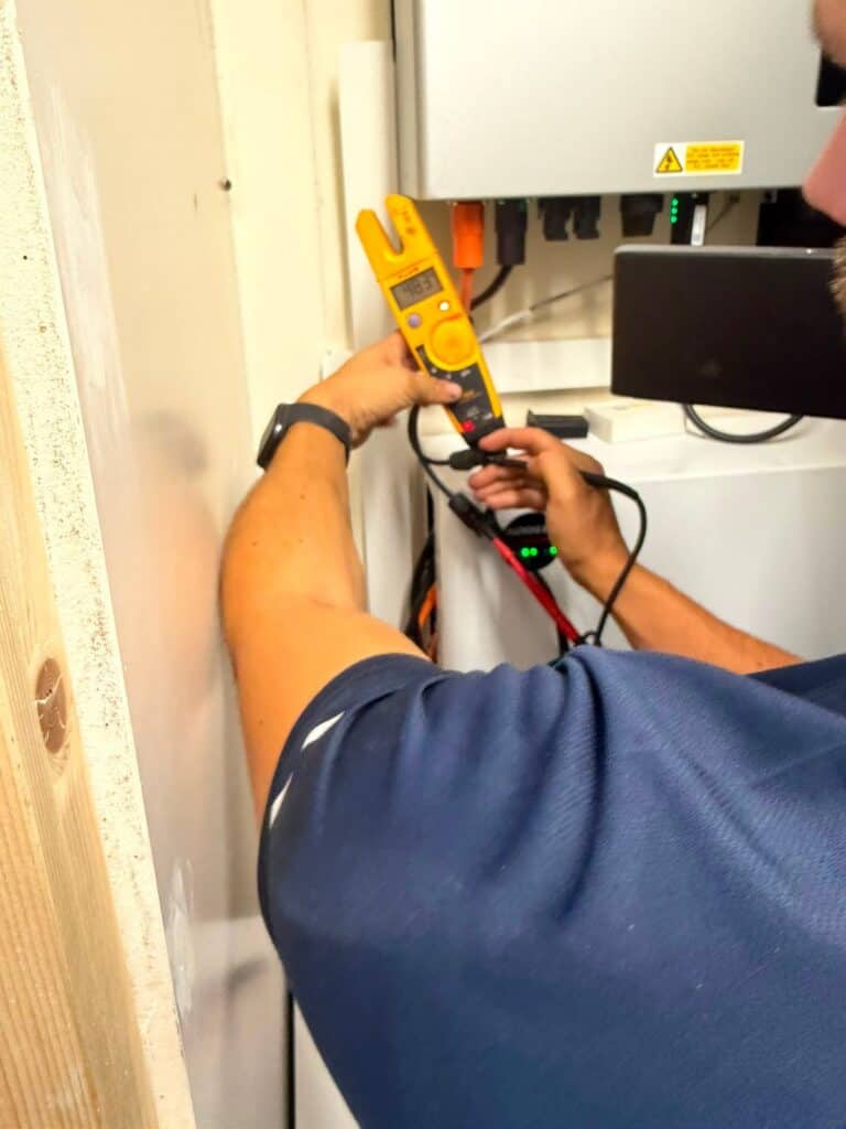 L&R engineer testing a solar and battery system with a clamp meter