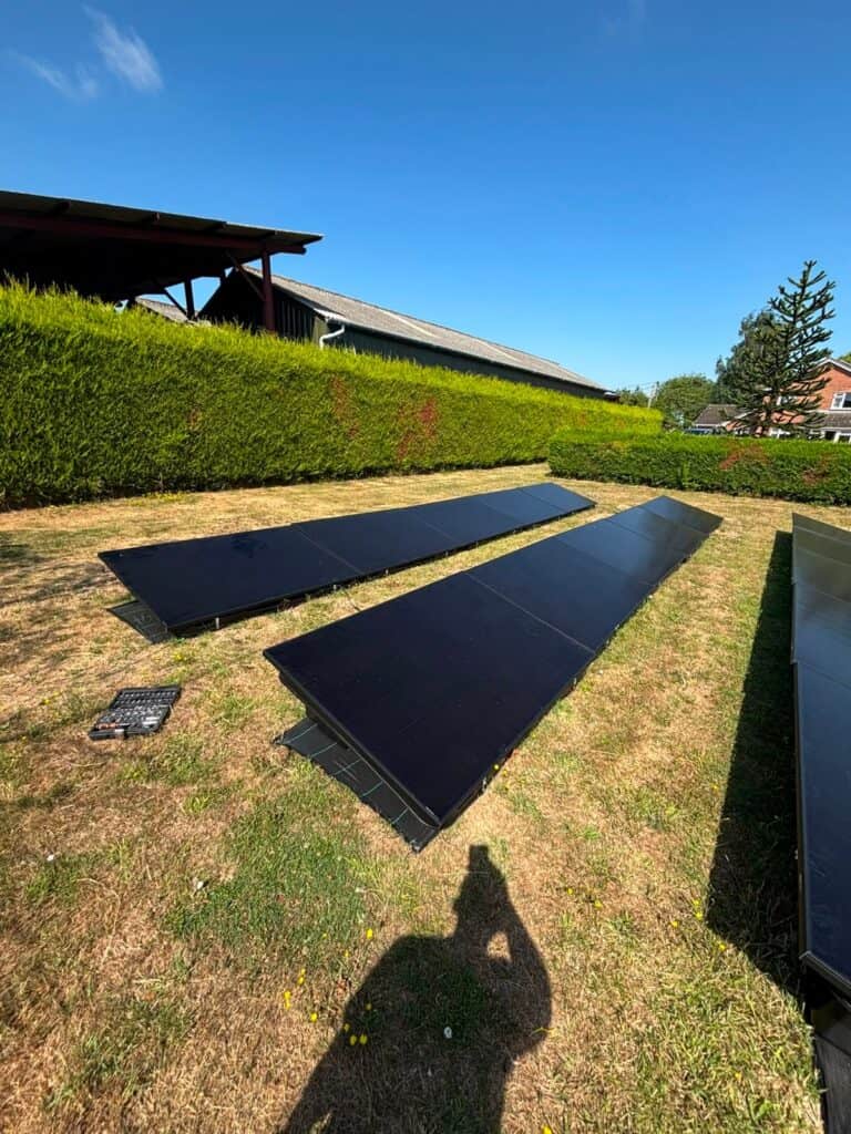 Rows of ground-mounted black solar panels on a lawn