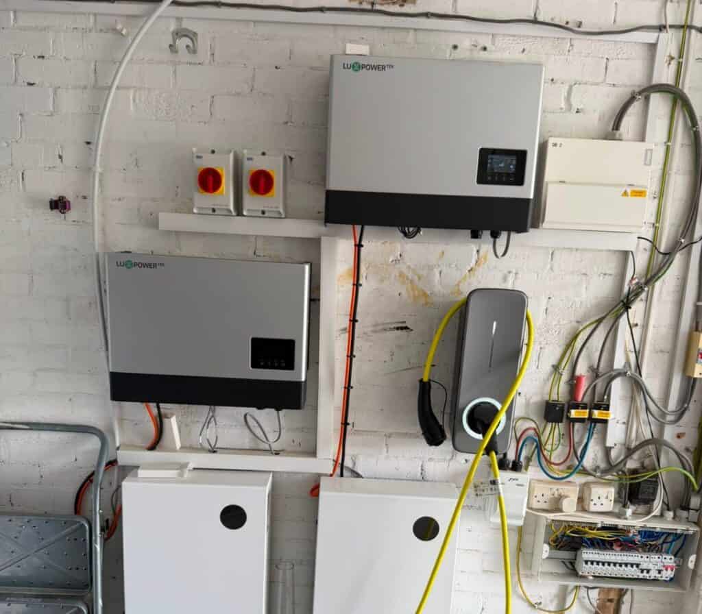 Two hybrid inverters, isolators and battery storage fitted on a garage wall