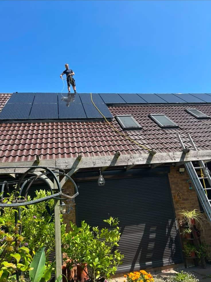 L&R engineer on a roof cleaning a row of black solar panels