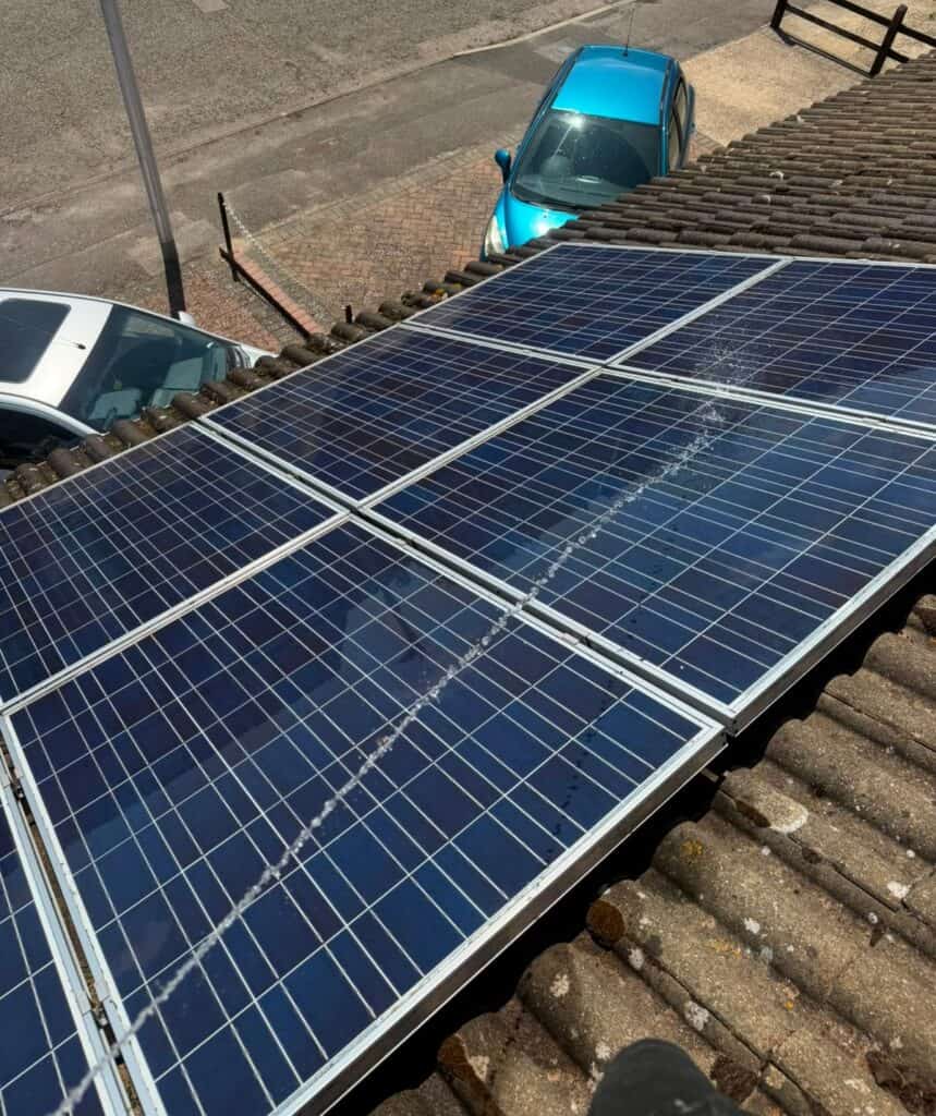 Older blue solar panels being rinsed during a clean